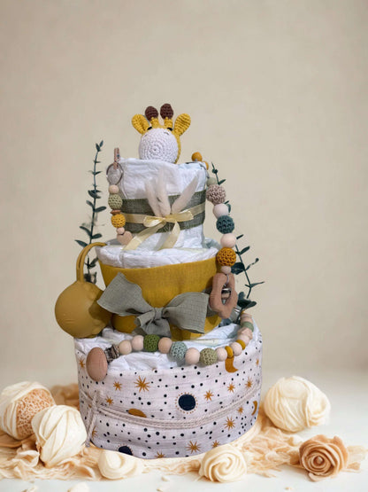 Safari giraffe diaper cake baby shower centerpiece featuring three tiers of rolled white diapers in warm mustard, olive, and neutral tones. The base tier is wrapped in celestial print fabric with tiny stars and moons, tied with rustic twine for a soft boho finish.

Middle tier accented with a mustard fabric band and sage green bow, complemented by a coordinating silicone and crochet beaded pacifier clip in earthy shades of olive, beige, and golden yellow. A matching mustard pacifier case is attached to the 