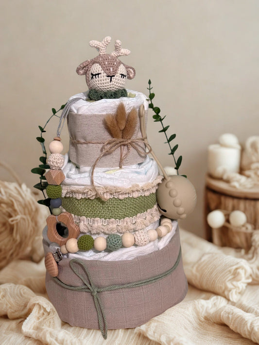 Rustic woodland deer diaper cake baby shower centerpiece featuring three tiers of rolled white diapers styled in soft sage, taupe, and natural linen tones. The base tier is wrapped in warm gray fabric and tied with muted green cord for a subtle, earthy finish.

The middle tier is accented with textured sage burlap and delicate lace trim, complemented by a coordinating silicone and crochet beaded pacifier clip in shades of olive, cream, dusty blue, and natural wood. A neutral pacifier case hangs neatly at th