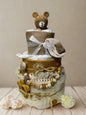 Sunshine teddy bear diaper cake baby shower centerpiece featuring three tiers of rolled white diapers styled in warm mustard, cream, and natural burlap tones. The base tier is wrapped in soft cream fabric with subtle rainbow and sunshine prints, tied with rustic raffia for a charming boho finish.

The middle tier showcases rich mustard fabric adorned with delicate sun and star motifs, accented with fringe trim and natural twine for added texture. A coordinating silicone and wooden beaded pacifier clip in sh