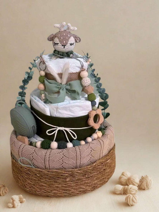 Woodland deer diaper cake baby shower centerpiece featuring three tiers of rolled white diapers wrapped in rustic burlap, soft sage ribbon, and a contrasting dark accent band with twine bow detail. Top tier decorated with a crocheted beige deer plush with delicate antlers, adding a charming forest-inspired touch.

Accented with eucalyptus greenery garland and silicone and crochet beaded pacifier clips in sage, forest green, cream, and natural wood tones. Includes a coordinating sage green pacifier case atta